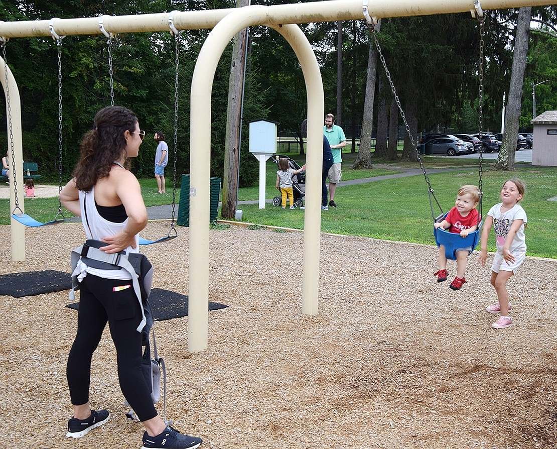 Rye Brook residents Brittany Sommer Katzin (left) and her daughter Brooke, a rising first-grader at Ridge Street Elementary School, take turns pushing Heath, the baby of the family, on a swing.