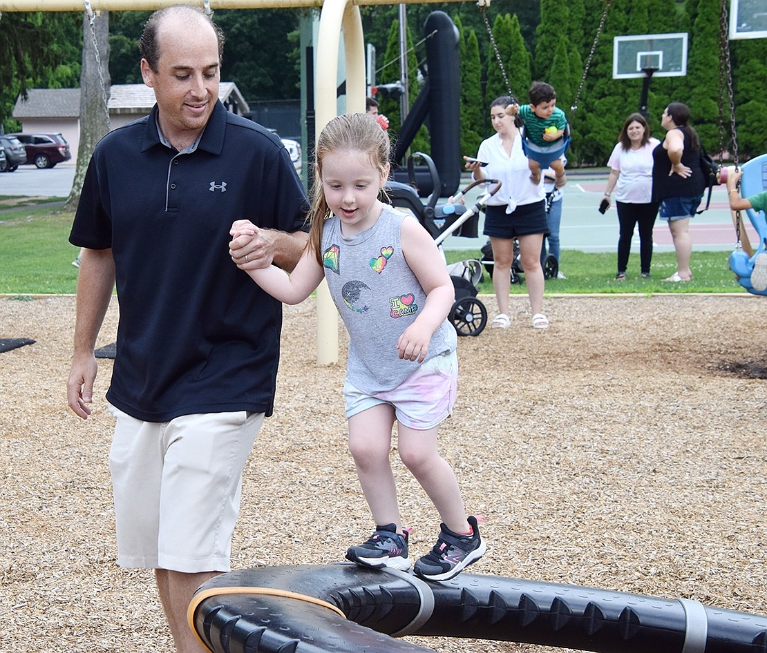 To get out the sugar rush, Rye Brook resident Jason Gartenlaub helps his daughter, Ella, keep her balance while playing at the Pine Ridge Park playground.