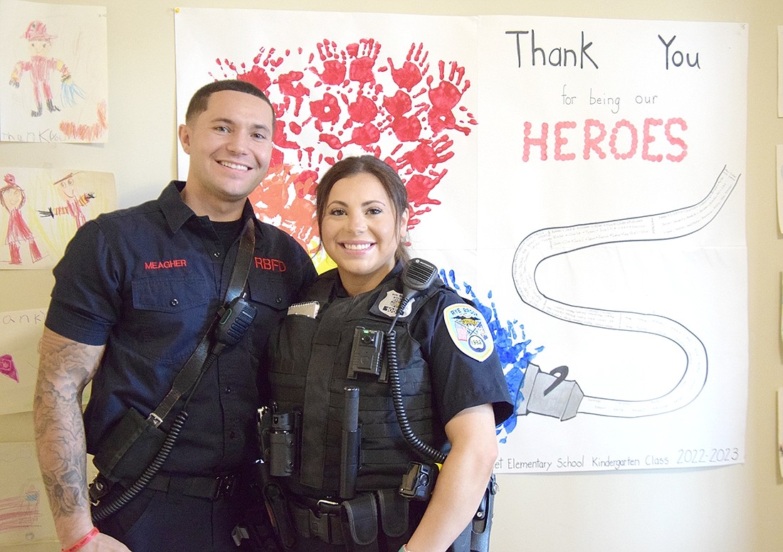 With a backdrop of Ridge Street Elementary School student-made artwork thanking local heroes for their service, Firefighter Michael and his sister Police Officer Amber Meagher stand together and smile for the camera in the Rye Brook Fire House on June 28 after discussing their ambitions to be first responders.