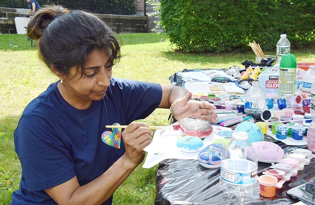 Pepita Lopez, a White Plains resident, paints a rock to be added to the new rock garden at the Weber Drive Housing Complex on Saturday, July 15.