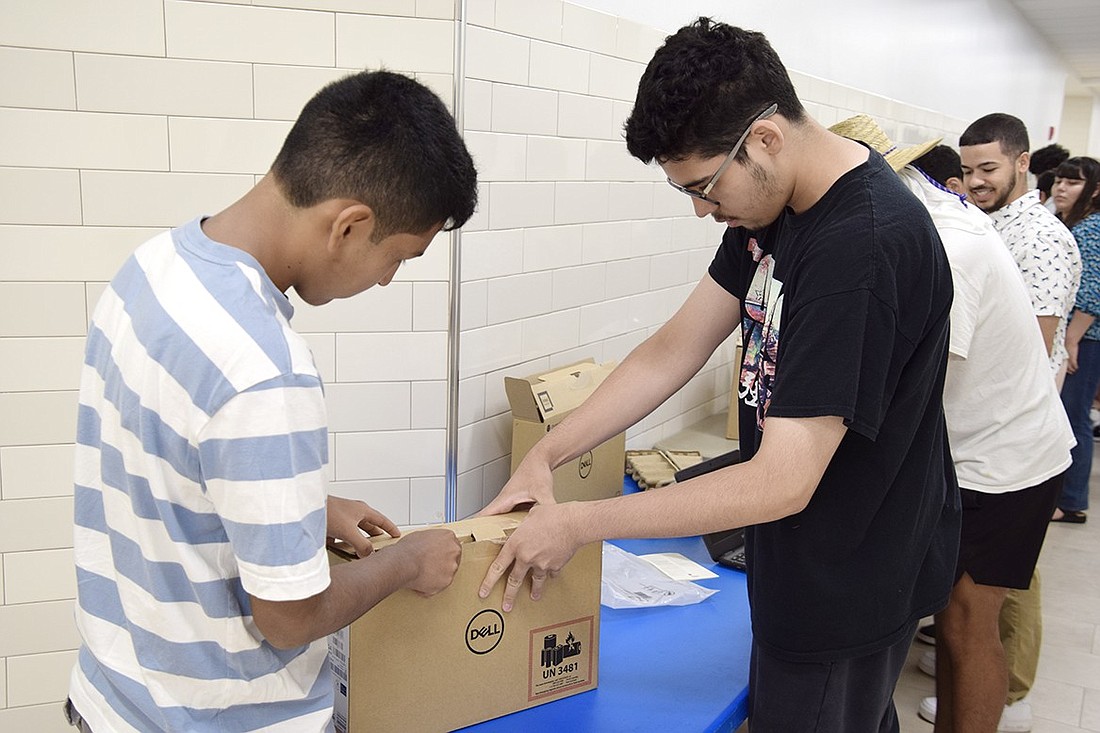 As interns with the Port Chester School District’s technology department, Port Chester High School rising seniors Pablo Gomez (left) and Anthony Enriquez unpack a new Chromebook and prepare to enroll it into the school’s network on Monday, July 24, at John F. Kennedy Elementary School.