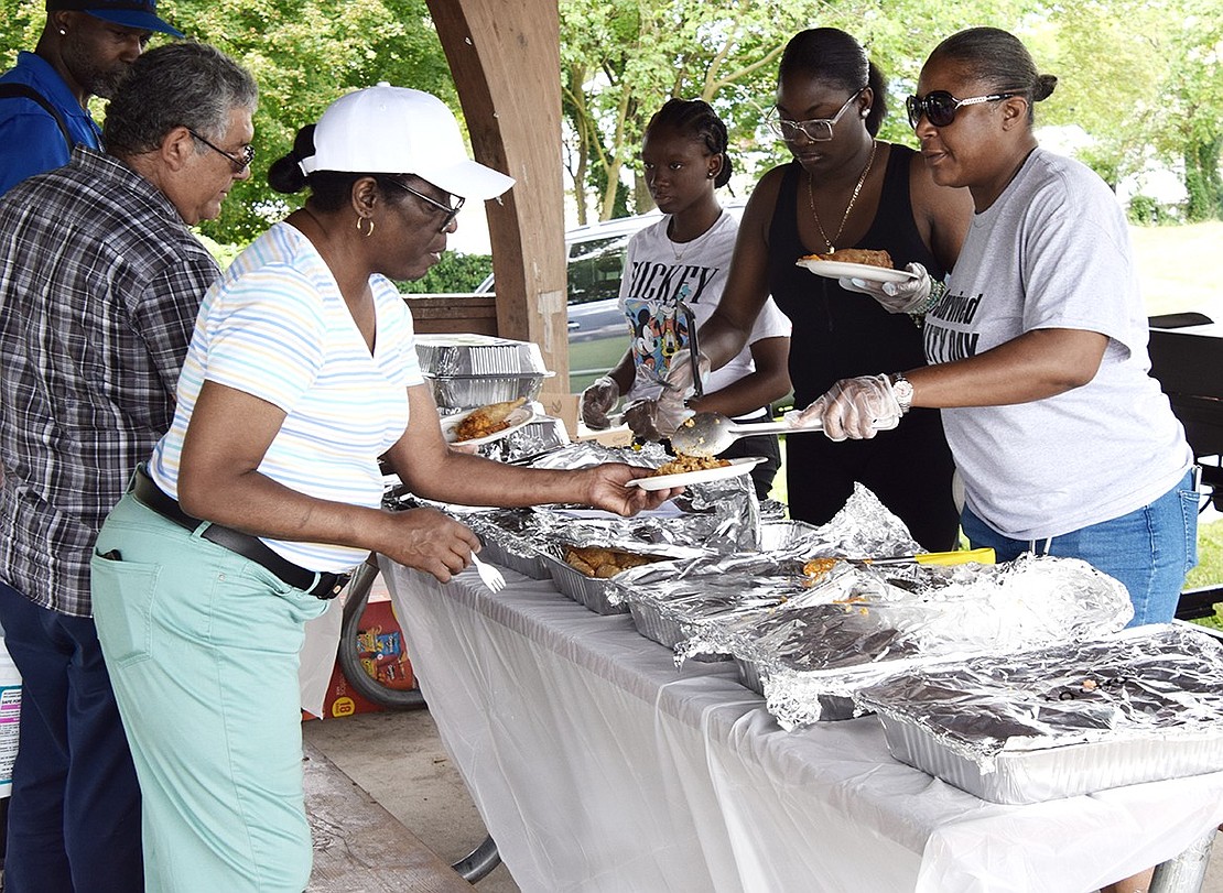 Purdy Avenue resident Angela Chambless serves food to Traverse Avenue resident Janet Rodriguez under the pavilion at Columbus Park.