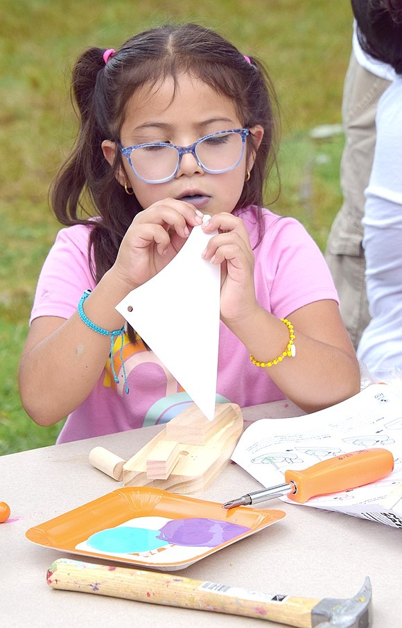 Johanna Garcia, 6, of Glen Avenue works diligently to attach the paper sail to the wooden sailboat her cousin helped her put together at The Home Depot-sponsored table where children and parents alike put their building skills to work.