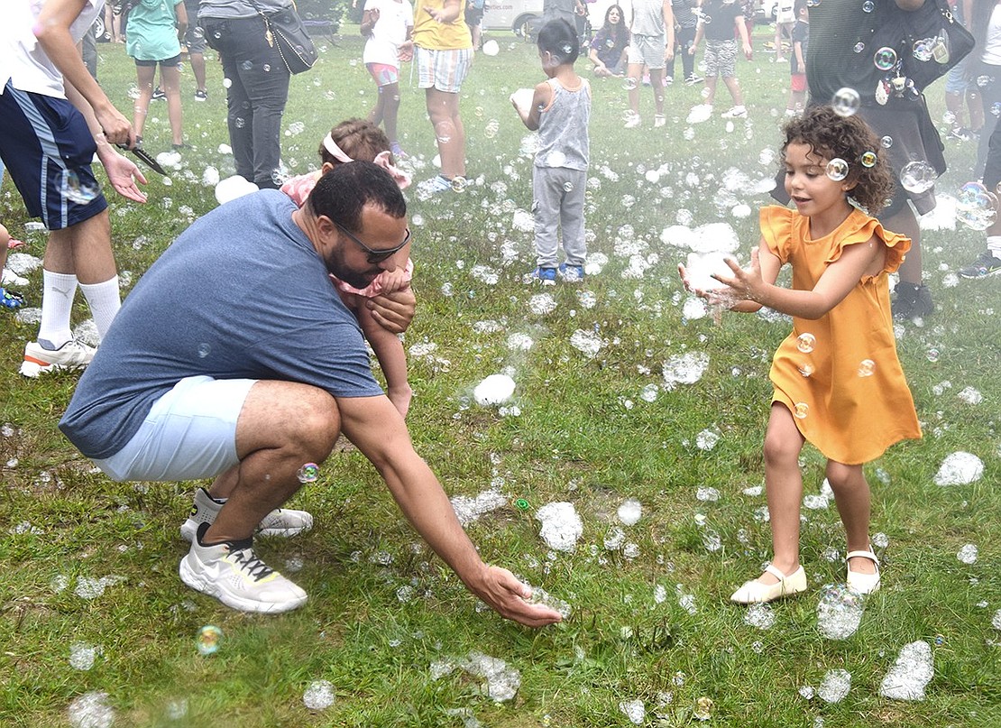 Port Chester Day on Saturday, Aug. 26, was a delightful celebration of the community spirit that makes the Village of Port Chester special. The Bubble Bus churning out bubbles throughout the afternoon at Lyon Park was a huge hit. Olivia Rocha, 4, of Willett Avenue takes hold of as many bubbles as she can gather while Bryant Romano, the new co-principal at Port Chester Middle School, scoops up some suds to show his youngest daughter.