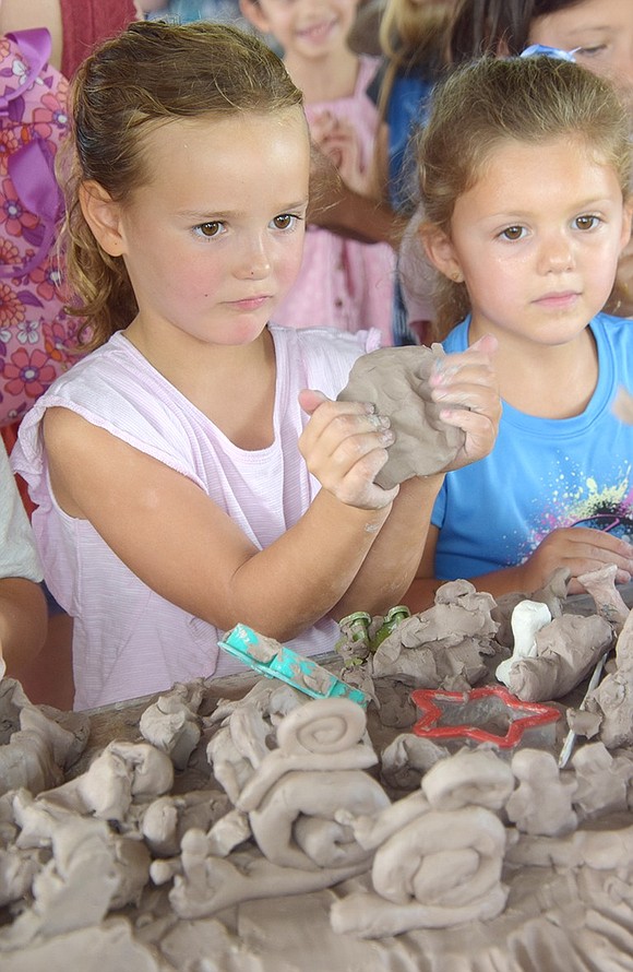 Mackenzie Toomb, 5, who will be a kindergartner at King Street School starting next week, delves into crafting in clay at a table under the gazebo sponsored by the Clay Art Center.