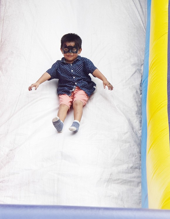 Little masked man, 3-year-old Matthew Sanan of Soundview Street, has no fear of slipping down the blowup slide time after time.