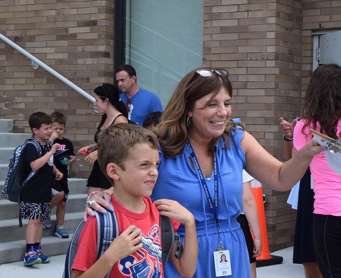 Third-grade teacher Julie Ciamei helps 7-year-old Jake Schorr spot his parents.