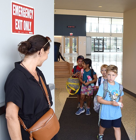Teacher’s aide Rosemary Edmonds holds the door open for one of the last groups of students on their way out.
