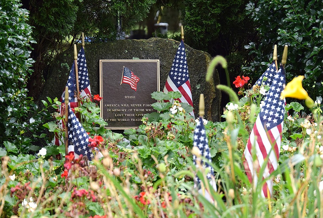 A plaque in memory of those who died at the World Trade Center 22 years ago during the Sept. 11 terrorist attacks sits surrounded by flags at the Village of Port Chester’s designated memorial in Lyon Park. The annual ceremony remembering the attacks and lives lost was cancelled this year due to an intense storm.