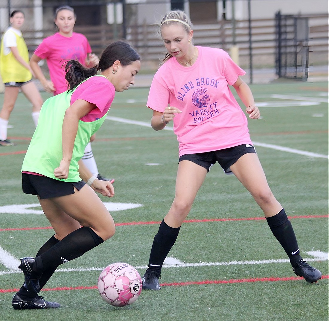 During practice, sophomore captain Kayleigh Curran maneuvers the ball around her opponent, senior Jessie Kron, and passes it to a teammate.