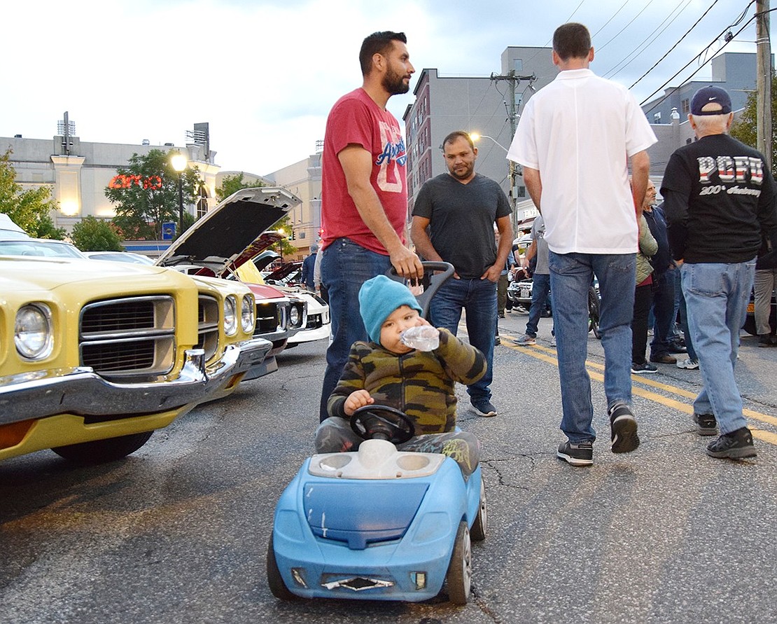 Ryan, a young child from Beech Street, brings his own car to the party with just a little pushing help from his father Francisco.