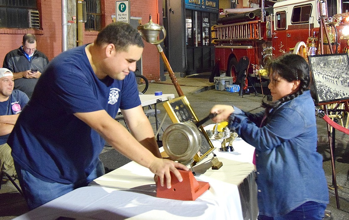 Connecticut-based Noroton Heights firefighter William Lopez shows Port Chester resident Daniella Flores Rosalel, 8, how to use a vintage fire truck siren.