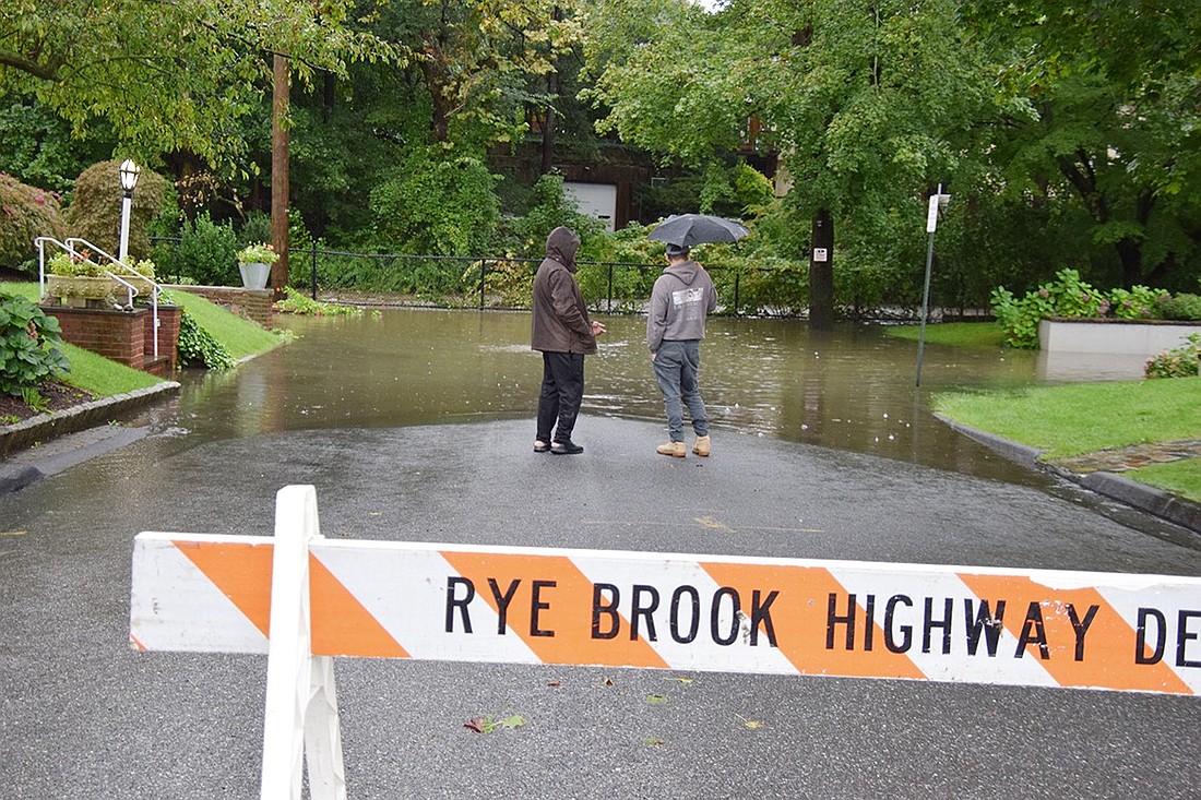 Two residents who live further up Wyman Street examine the water backed up at the foot of the street along the Blind Brook on Friday afternoon, Sept. 29, during the damaging rainstorm that walloped the area starting Thursday evening.