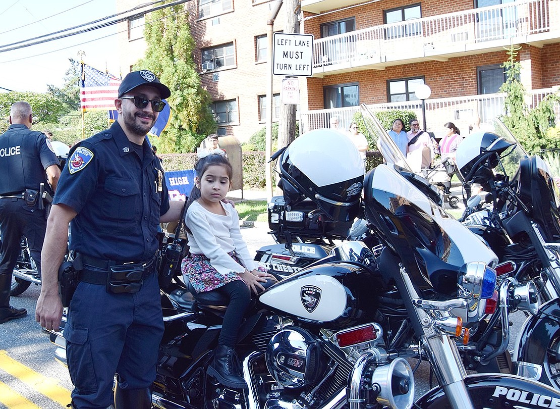 Port Chester Police Detective Leonard Carriero poses for a photo with Port Chester resident Daleyza Valdovinos on his motorcycle before the parade starts.