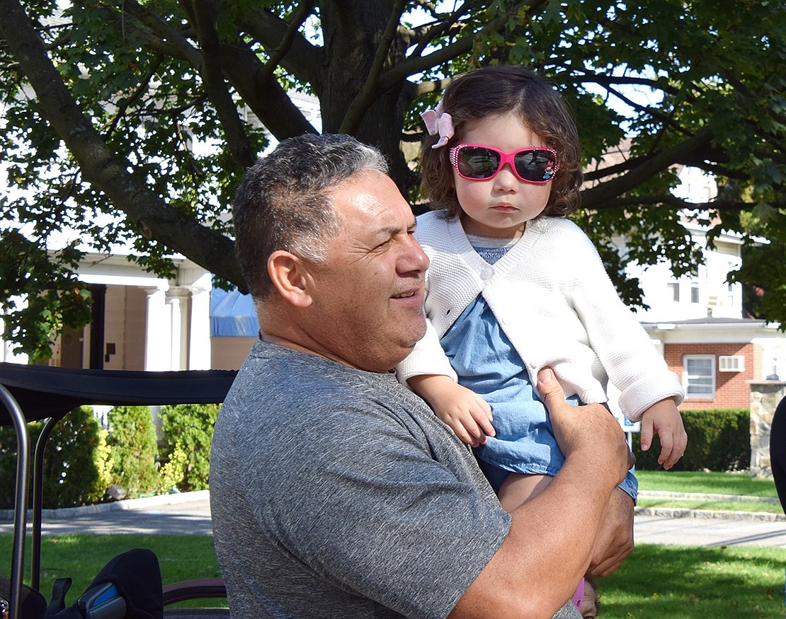 Irving Avenue residents Adan Hernandez (left) and Addison Dueñas watch the festivities stroll by in a nice shady spot on Westchester Avenue.