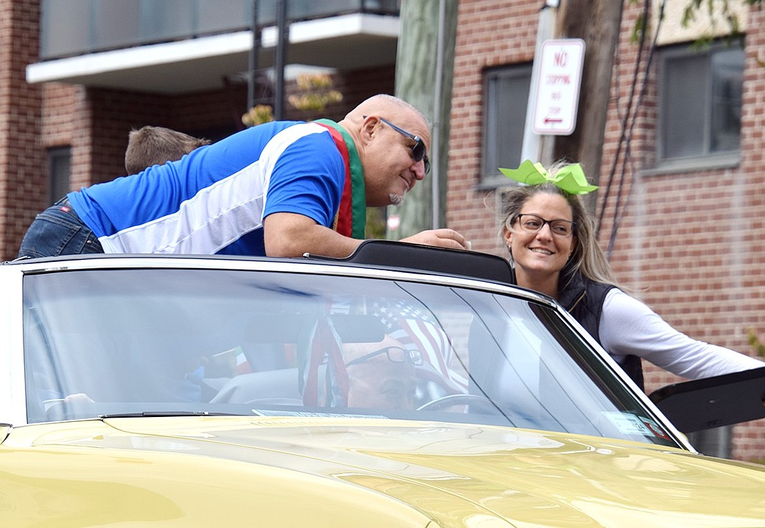 Ricky Marini, the parade grand marshal, leans across the yellow Pontiac LeMans convertible he rides in to give his daughter in-law Karen Marini a kiss on the cheek.