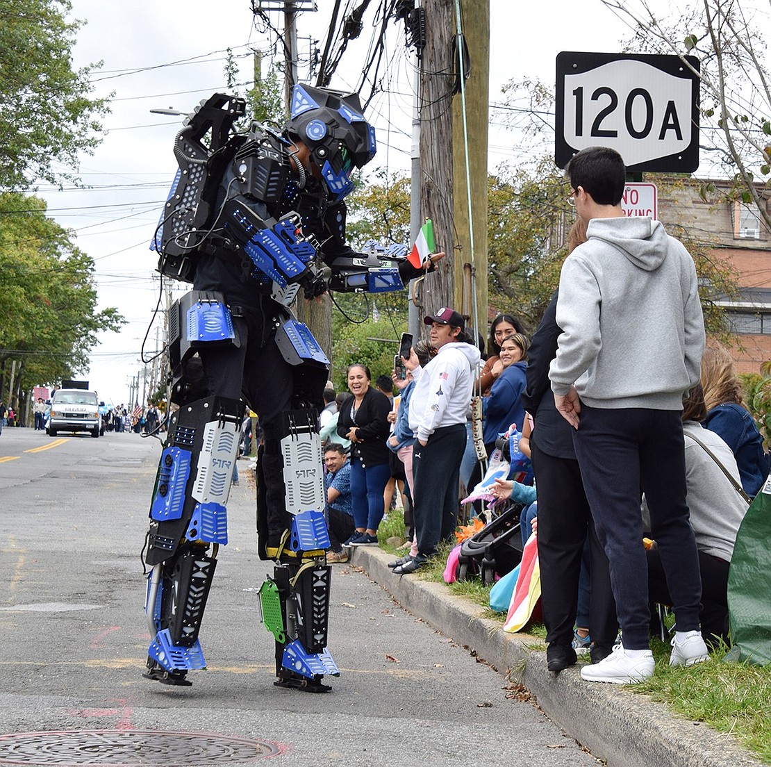 With tiny Italian flags in hand, a dancing robot entertains parade spectators as they strut down Westchester Avenue.