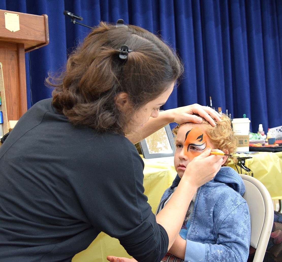 Maggie Sauerwine, of Making Faces Parties Inc., paints tiger stripes onto the face of 4-year-old Nolan Hoch, from Rye Brook.