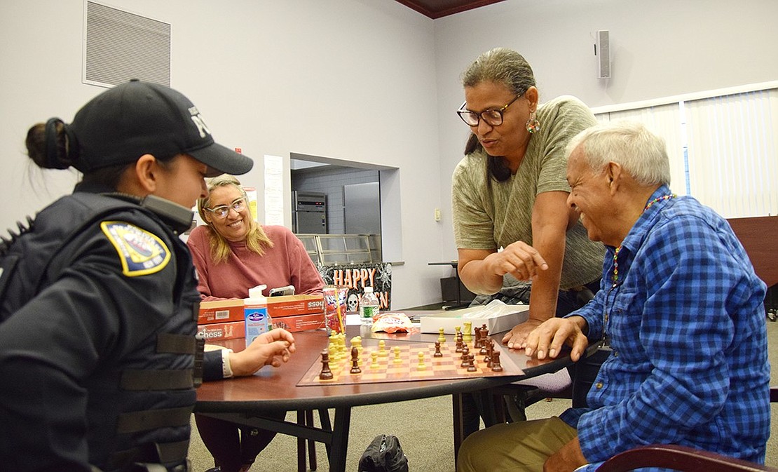 Police Officer Leslie Gutelius (left) gets a strategy crash course from Port Chester residents Grace Cueto and Cristina Jupiter in her attempt to beat West Glen Avenue resident Pedro Cueto.