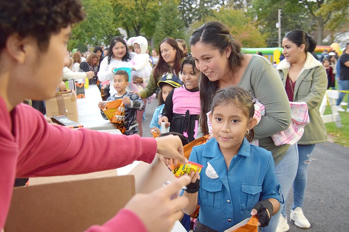 Volunteers, like Port Chester High School senior Joseph Alvarez, give out candy to the hundreds of trick-or-treaters like King Street School first-grader Danna Mendez, who’s dressed up as a police officer. Port Chester’s Halloween in the Park saw a variety of children and adults alike dressing up for some fun at Lyon Park on Wednesday, Oct. 25.