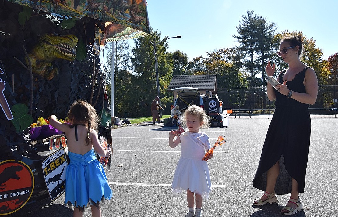 Three-year-old twins Mia (left) and Audrey grab some candy out of the Jurassic Park themed car at the Village of Rye Brook’s first Trunk-or-Treat event. Their mom, Rye Brook resident Julie Taub, keeps a lookout for any rogue dinosaurs.