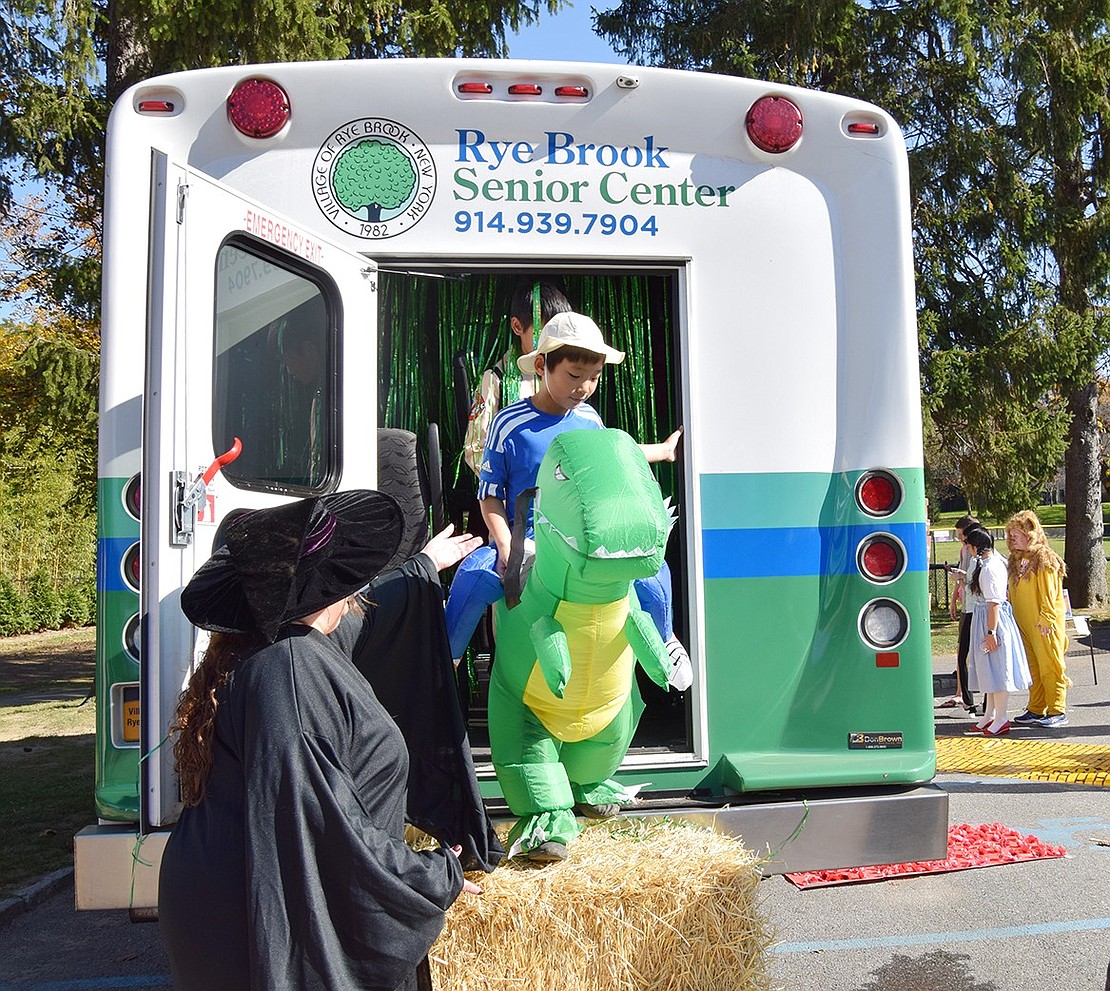 Rye Brook dinosaur rider Andrew Chen, 11, steps down from the Wizard of Oz themed attraction set up inside the Rye Brook Senior Center shuttle bus.