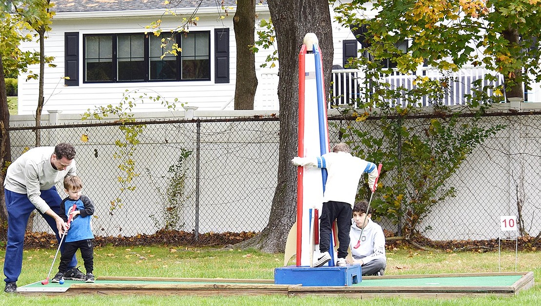 Rye Brook resident Scott Schwartz gives his 3-year-old son Carter some guidance on the 10th hole. His older son, 5-year-old Lucas, scouts the rocket ship obstacle.