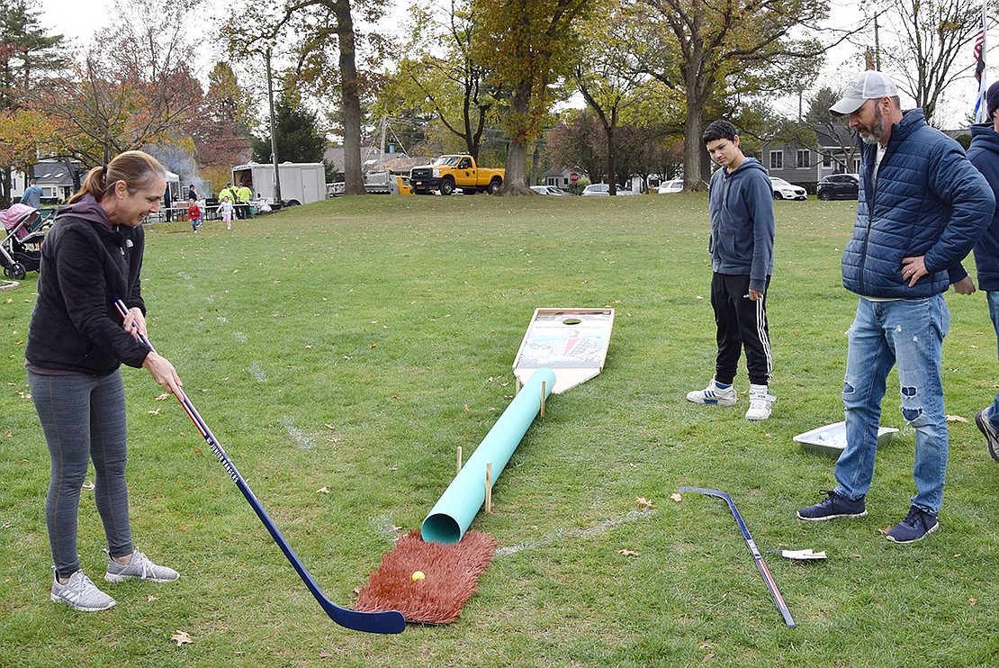 Rye Brook resident Nancy Cirillo tries her hand at the tricky final hole as her son Felix Cuesta, a sophomore at Blind Brook High School, and husband Vinny watch.