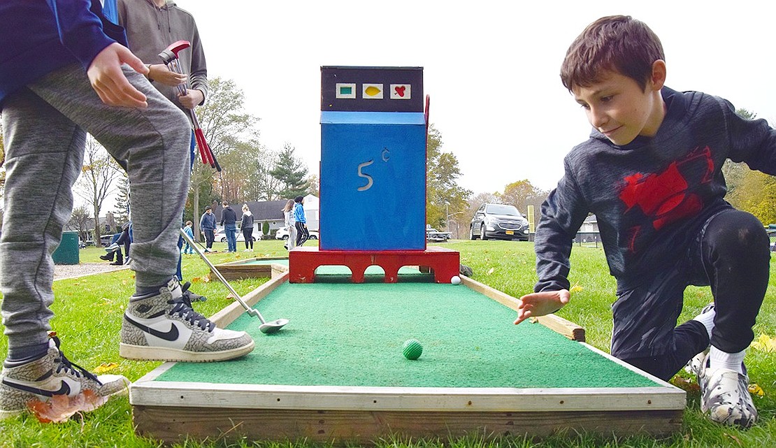 Dylan Stein (right), 9, places the ball for his older brother Jake on the penultimate hole. Taking putt-putt seriously, the boys, who attend Ridge Street School and Eagle Hill School, respectively, brought their own clubs to the park.