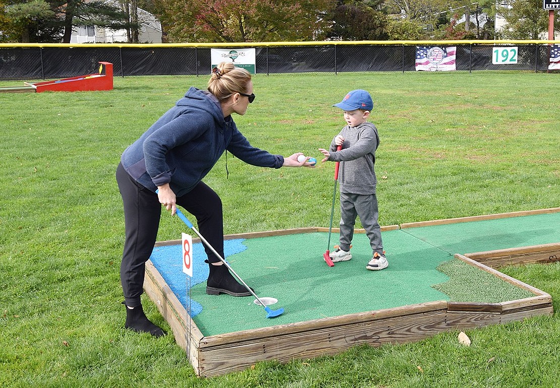 Rye Brook resident Emily Schwartz hands her son, 4-year-old Sebastian, his golf ball after he successfully conquered the eighth hole.