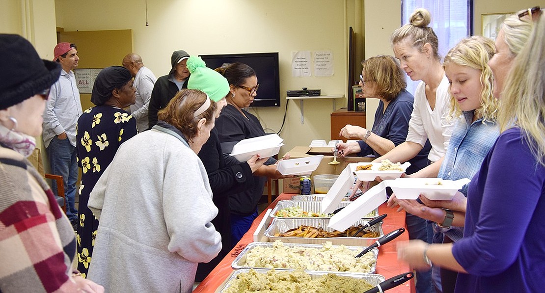 Volunteers with Corporate Outreach, a Westchester-based organization, serve Thanksgiving dinners in the community room at the Drew Street senior apartments to a line of residents going out the door. The event, held in association with the White Plains Salvation Army, provides food for tenants of public housing. This year, dinners were provided at both senior housing complexes in Port Chester—on Drew Street and Terrace Avenue.