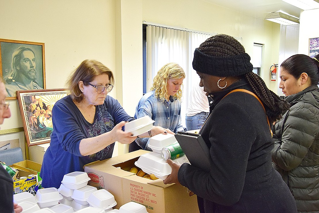 Robin Goldstein (left), a volunteer from Eastchester, helps Maria Pride stack up on Thanksgiving food. Pride is picking up a meal for her mother, who could not attend.