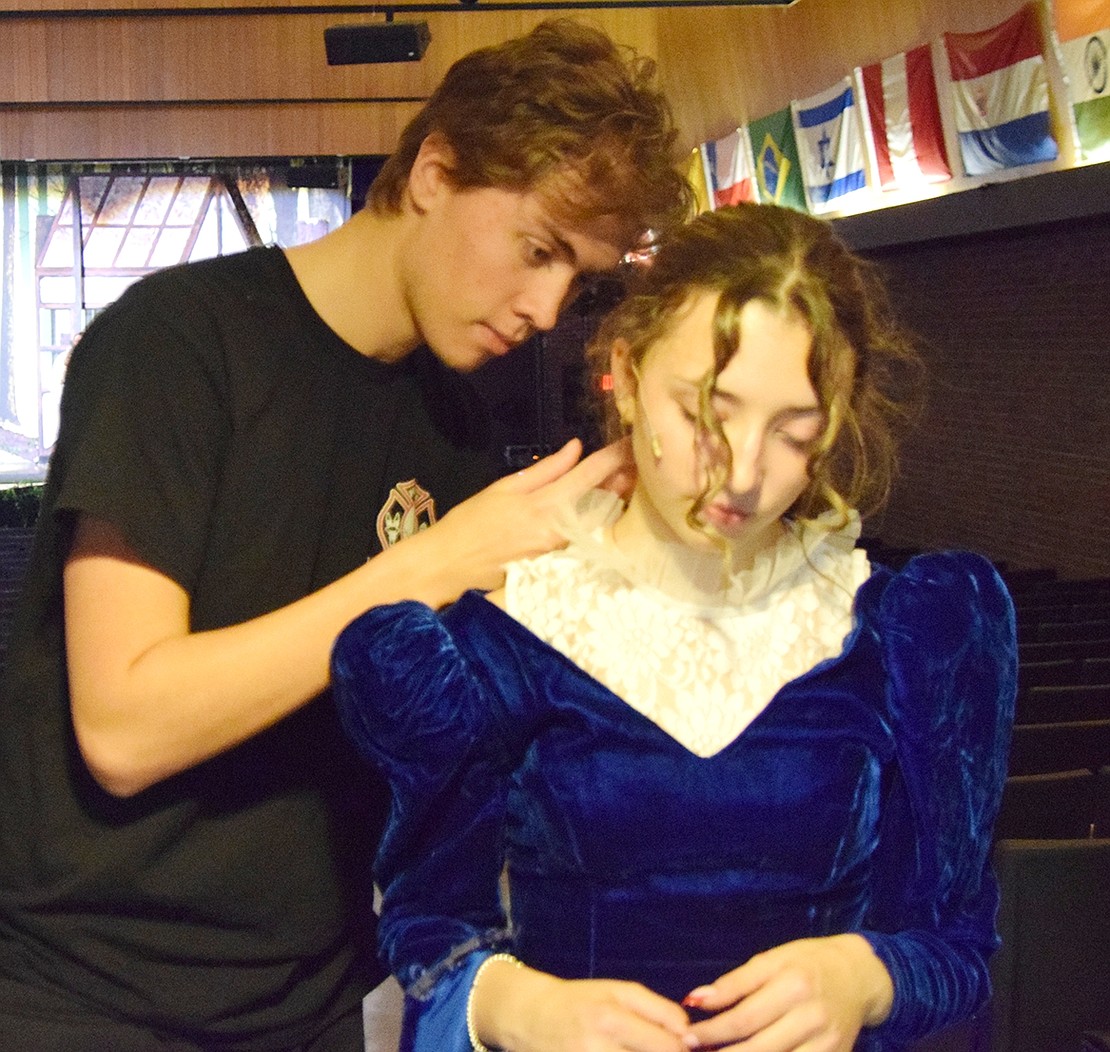 Julian Silva (left), a Blind Brook High School Class of ’23 graduate in charge of sound for the show, helps eighth-grader Deanna Berlingo with her microphone. Berlingo is playing Cinderella’s stepmother.