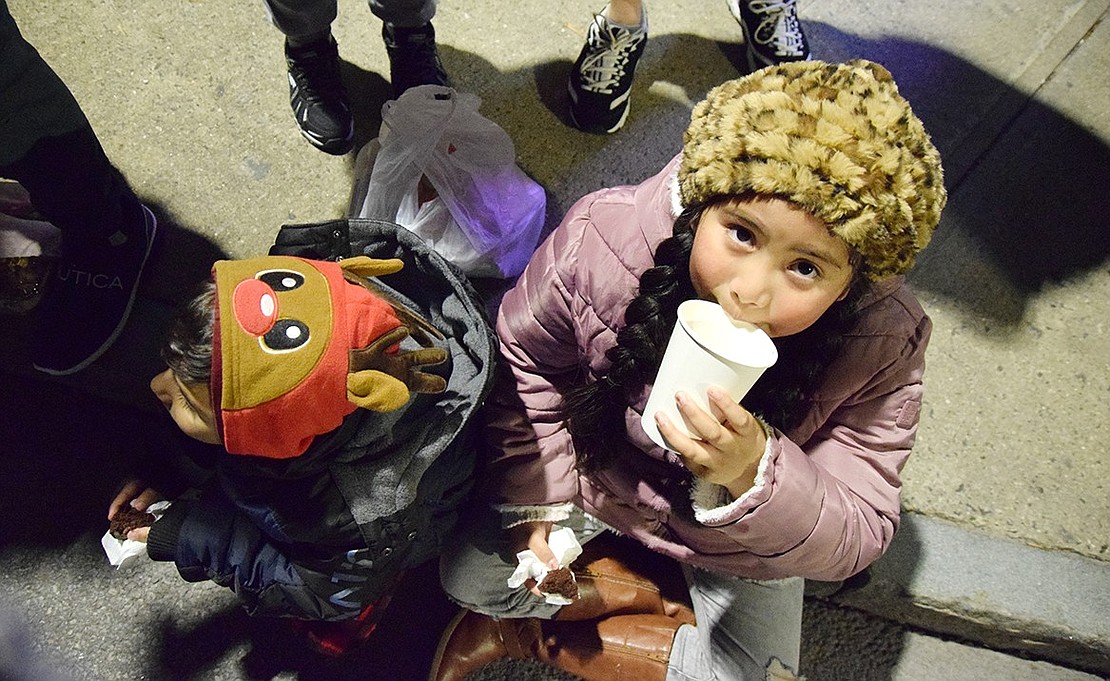 Damian Peraza (left) and Adriana Munoz, young children of Port Chester, enjoy baked goods and hot chocolate provided by the Salvation Army before the festivities begin.