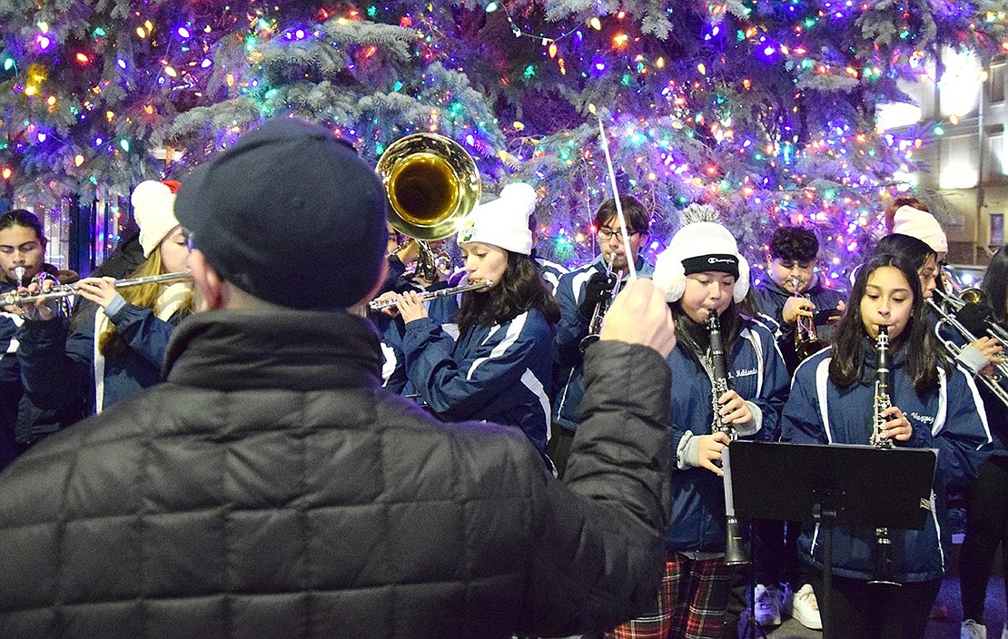 Port Chester High School band director Mike Miceli guides musicians such as clarinetists Camilla Vasquez (right), a sophomore, and Kimberly Maldonado, a senior, through holiday tunes for attendees.