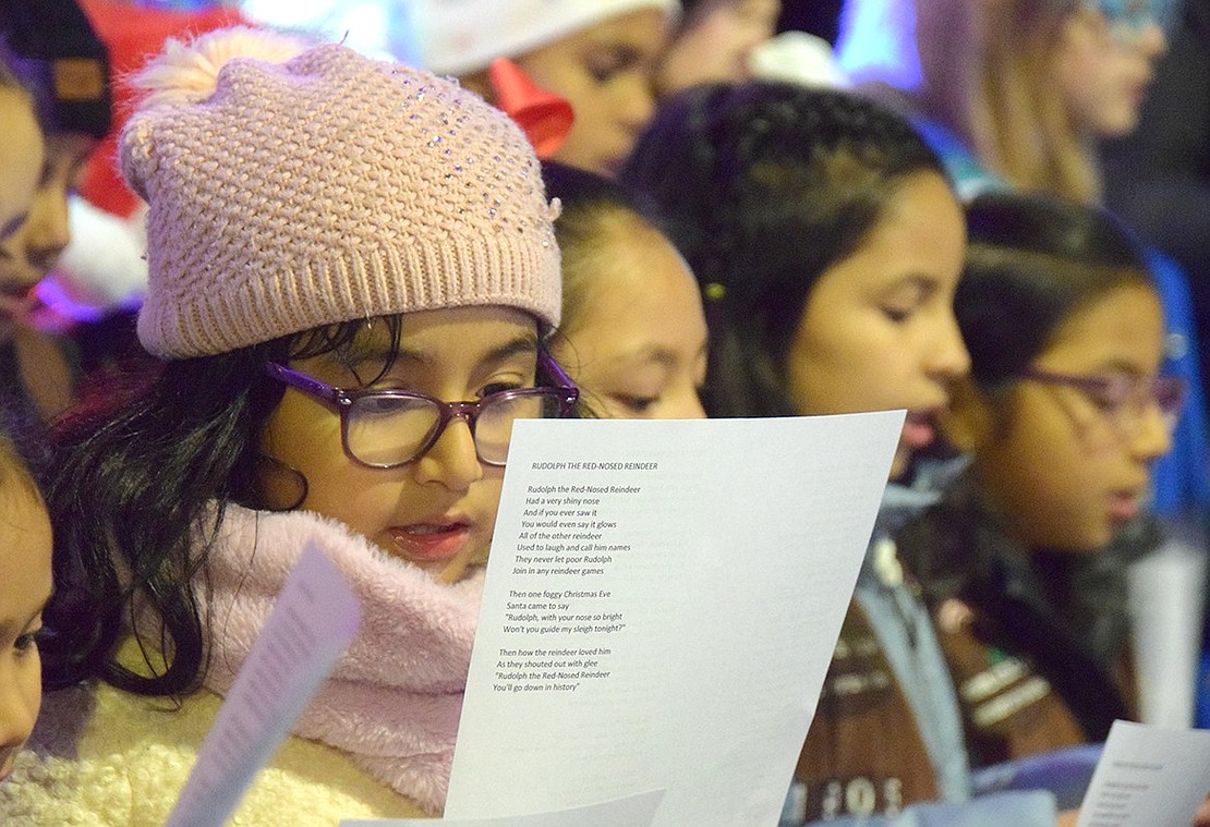 Performing with multiple Girl Scout troops, John F. Kennedy School third-grader Sofia Rodriguez has her eyes peeled on the lyrics as she sings “Frosty the Snowman.”