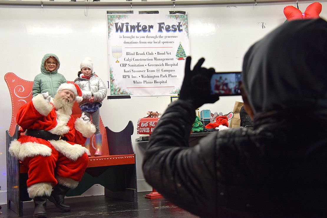 Ridge Street School third-graders Gabi Ferdschneider (left) and Taylor Cirillo pose with Santa Claus while Vincent Cirillo snaps a picture.