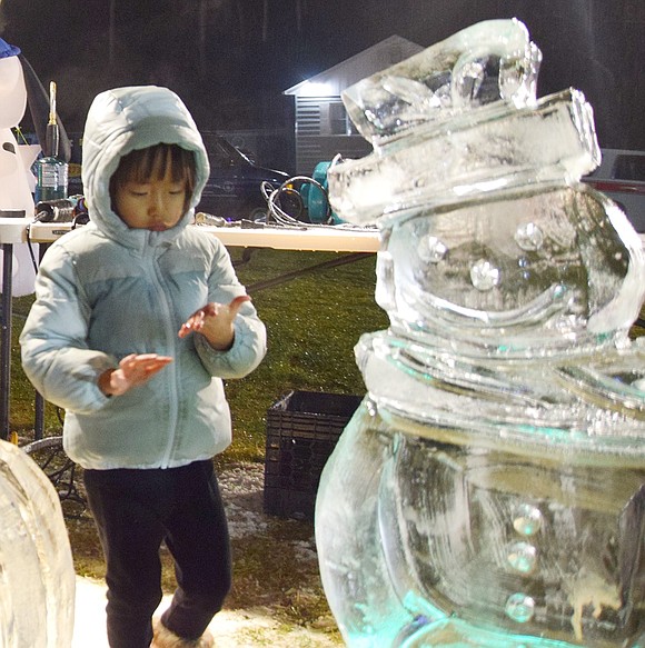 Elica Hashimoto, a 4-year-old from Rye Brook, entertains herself by patting down the ice sculptures carved by Rich Daly, the master ice carver from Ice Memories—a Long Island-based company.