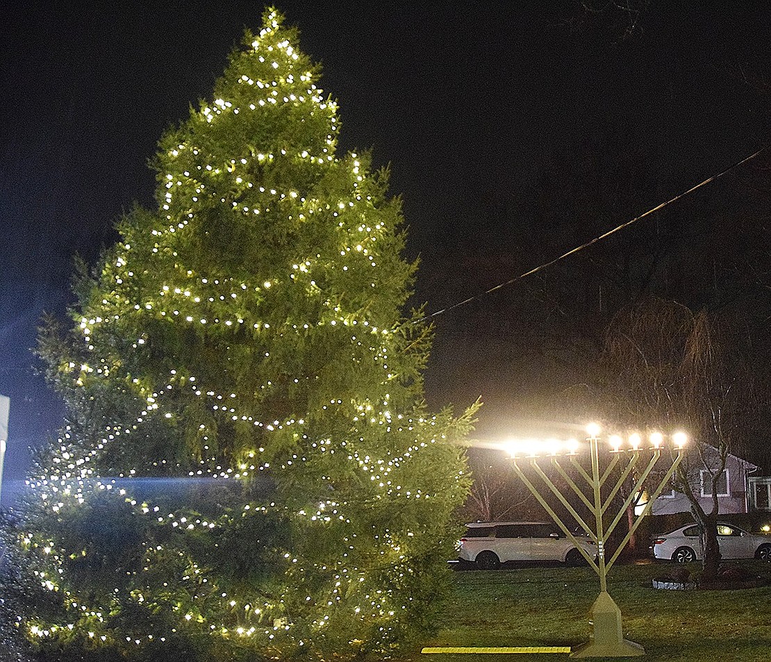 The tree and menorah serve as beacons of light on the dark, rainy evening.