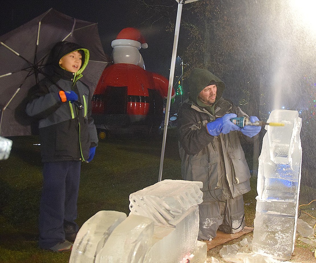 Marco Colmenares (left), a third-grader at Ridge Street School, watches with mouth agape as Rich Daly carves out a Santa Claus sculpture from a block of ice. Despite the rain, Colmenares was among the many who withstood the storm on Friday, Dec. 1, to stop by Pine Ridge Park and celebrate the holidays at the annual Winterfest event.