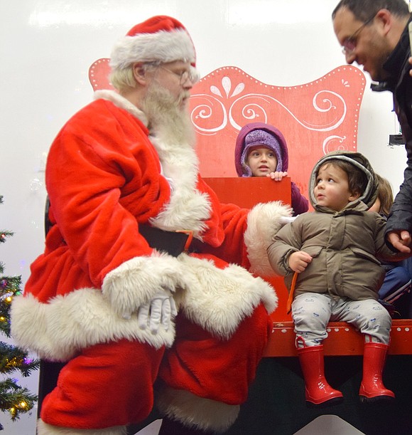 Noah Gangitano, a 2-year-old from West Harrison, keeps a wary eye on Santa Claus. Meanwhile, 4-year-old Adrianna Carroll from Rye Brook, peeks out from behind Santa.