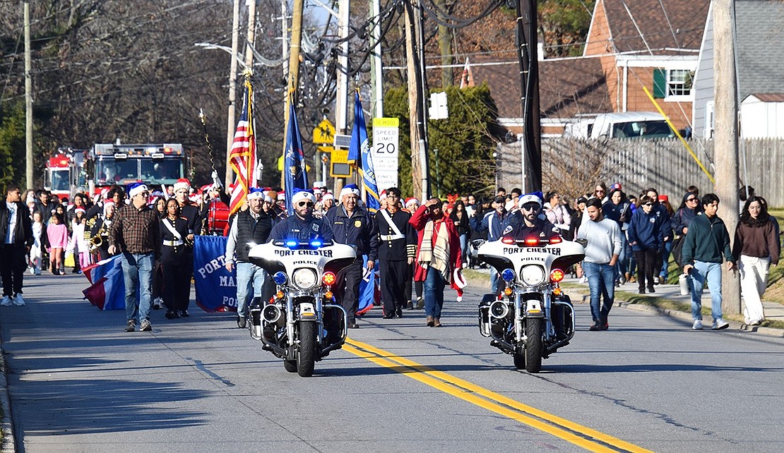 Port Chester police officers, Village officials, Port Chester High School musicians and elementary school students strut down King Street during the Christmas Parade, leading fire engines drawing the Clauses to Lyon Park.