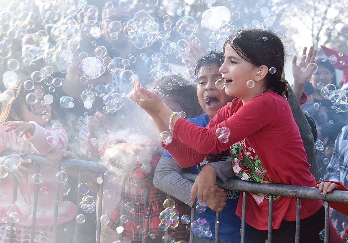 Surrounded by peers equally hyped to play with the bubbles spewing out of a machine, Edison Elementary School third-grader Inara Vokshi embraces a magical moment by leaning over the railing to cradle a cluster of suds.