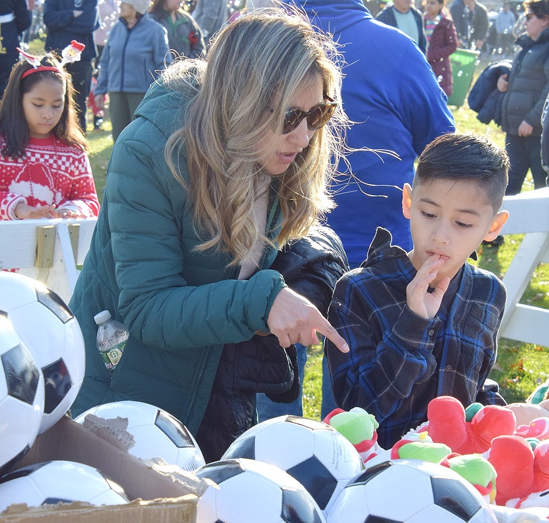 With so many options on the table, King Street School second-grader Andrew Fernandez thinks hard about which gift to choose, taking the decision seriously. Luckily, his mother Rose is there to help.