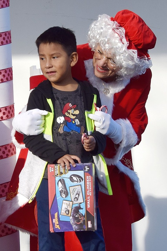 John Ramon, a Port Chester 6-year-old, holds his new Marvel-themed remote-controlled car while accepting a little hug from Mrs. Claus.