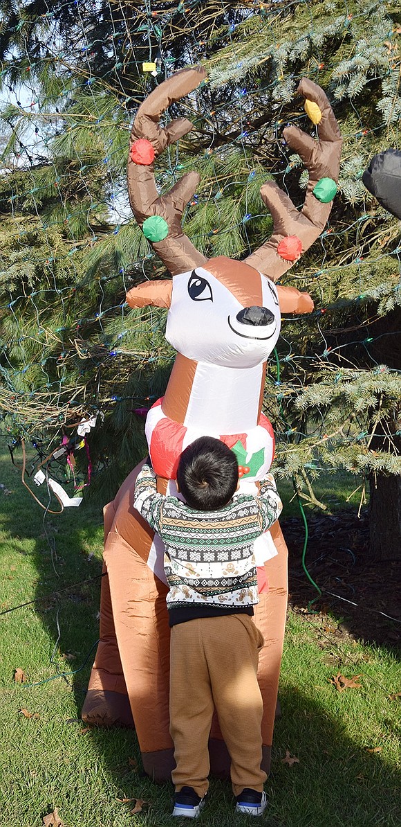 When asked what holiday inflatable he wants to pose with, Port Chester 2-year-old Miguel Carranza toddles to a reindeer and hugs it.