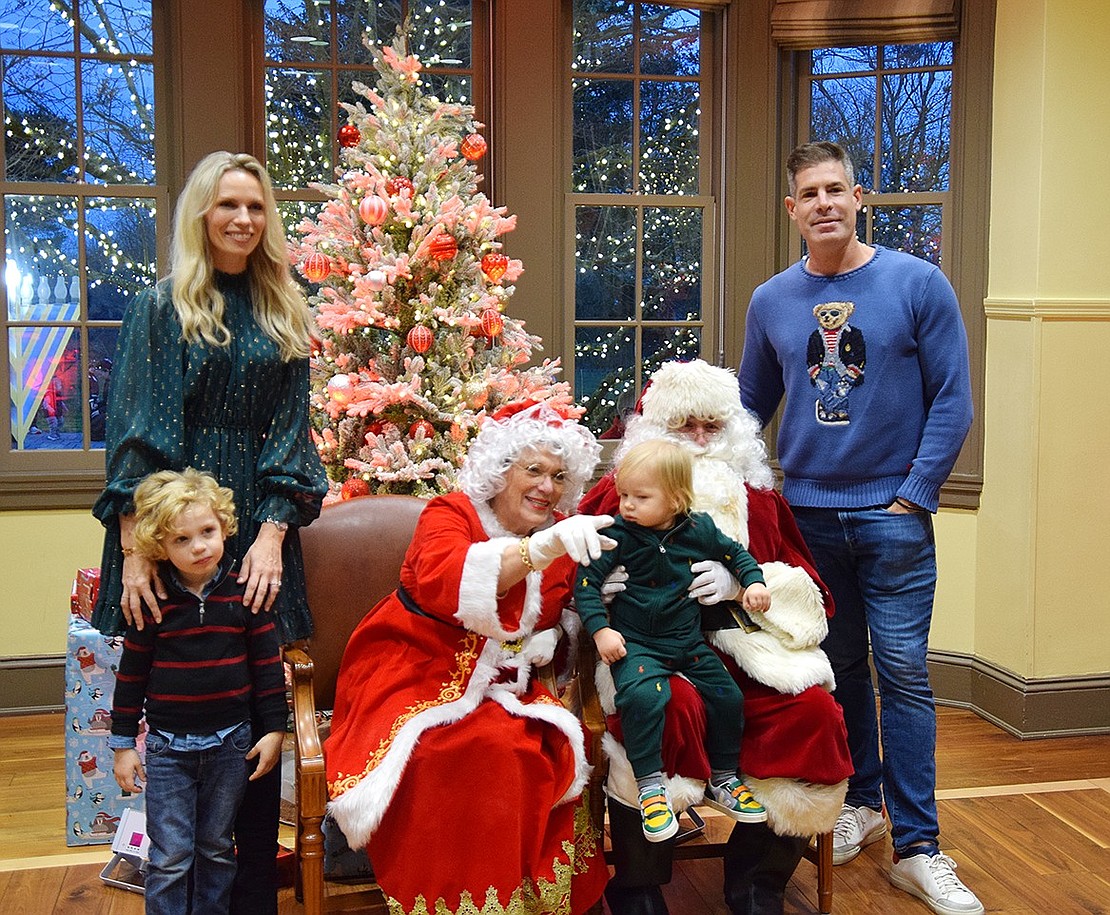 Mrs. Claus tries to get 3-year-old Leo Distasio of Greenwich, Conn., to look at the camera while he sits on Santa’s lap. His parents Gaby and Frank stand on the sides with his older brother, 7-year-old Blake.