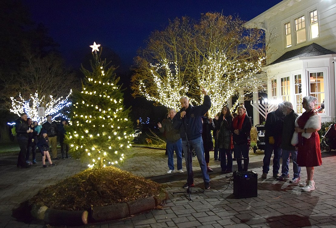 Rye Town Supervisor Gary Zuckerman celebrates the lighting of the Christmas tree and menorah outside the Crawford Mansion Community Center, lauding the work of those who made the event possible.