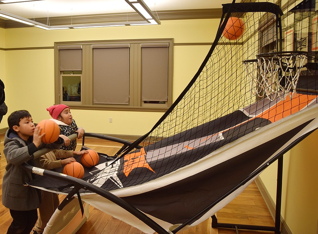 Port Chester siblings 8-year-old Ian (left) and Mia Larios, 6, take their shots at the basketball game set up in an upstairs room of the Crawford Mansion Community Center.