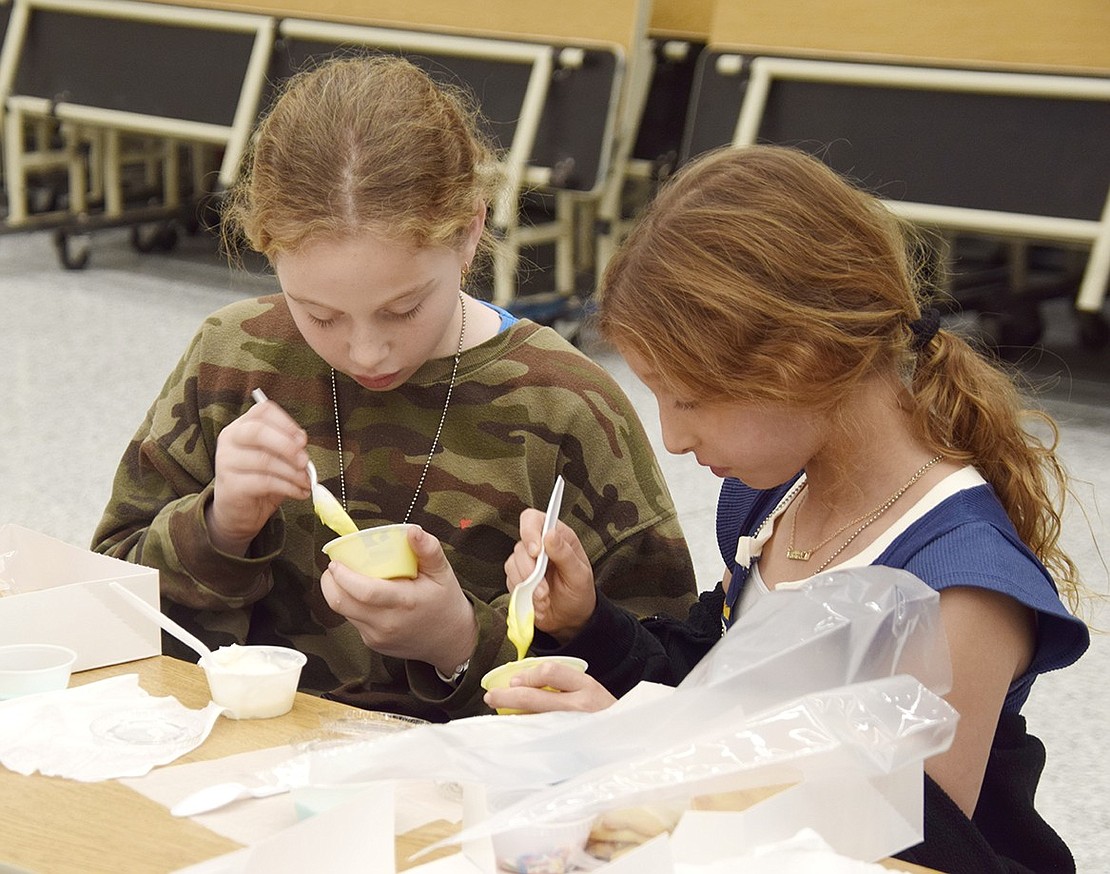 What was once too thick becomes a little too watery. Fourth-graders Abigail Gitkind (left) and Annabelle Zigler are starting to realize there’s a certain art and tact to stirring up the perfect frosting consistency.